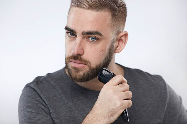 man trimming beard with beard trimmer