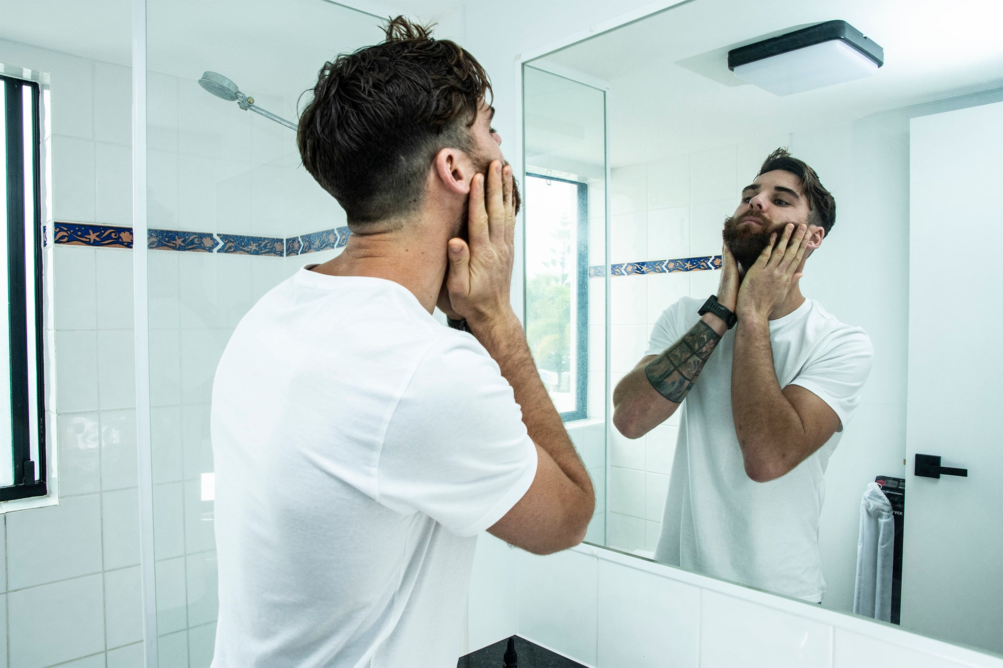 man applying beard oil in the bathroom