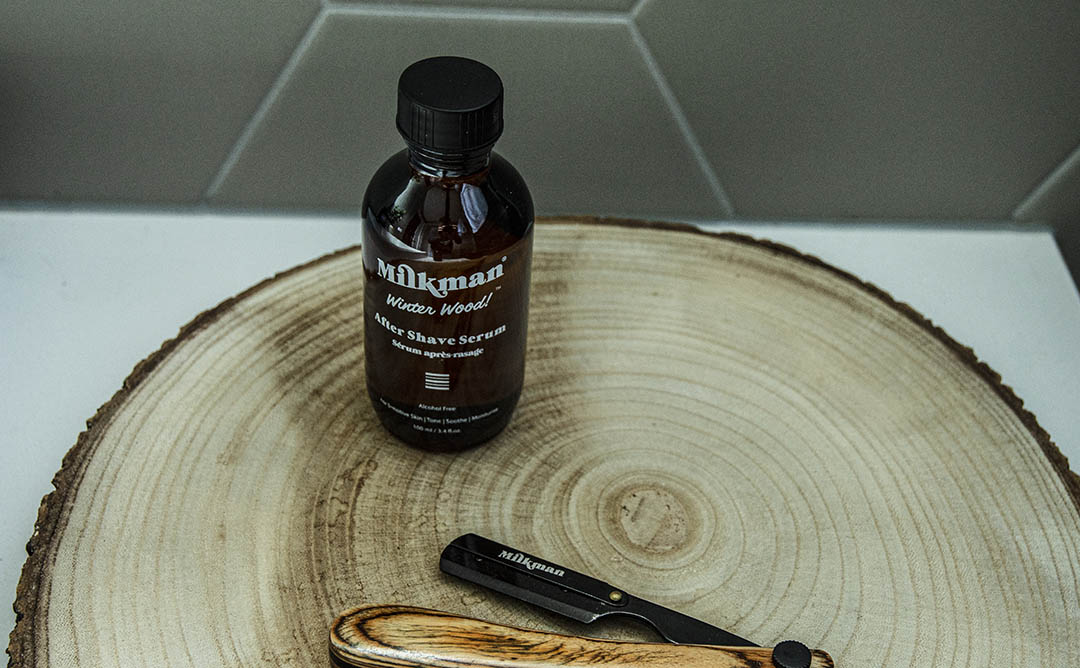 milkman after shave serum next to a cut throat razor blade