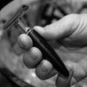 a man hand holding a straight razor double edged with a black handle